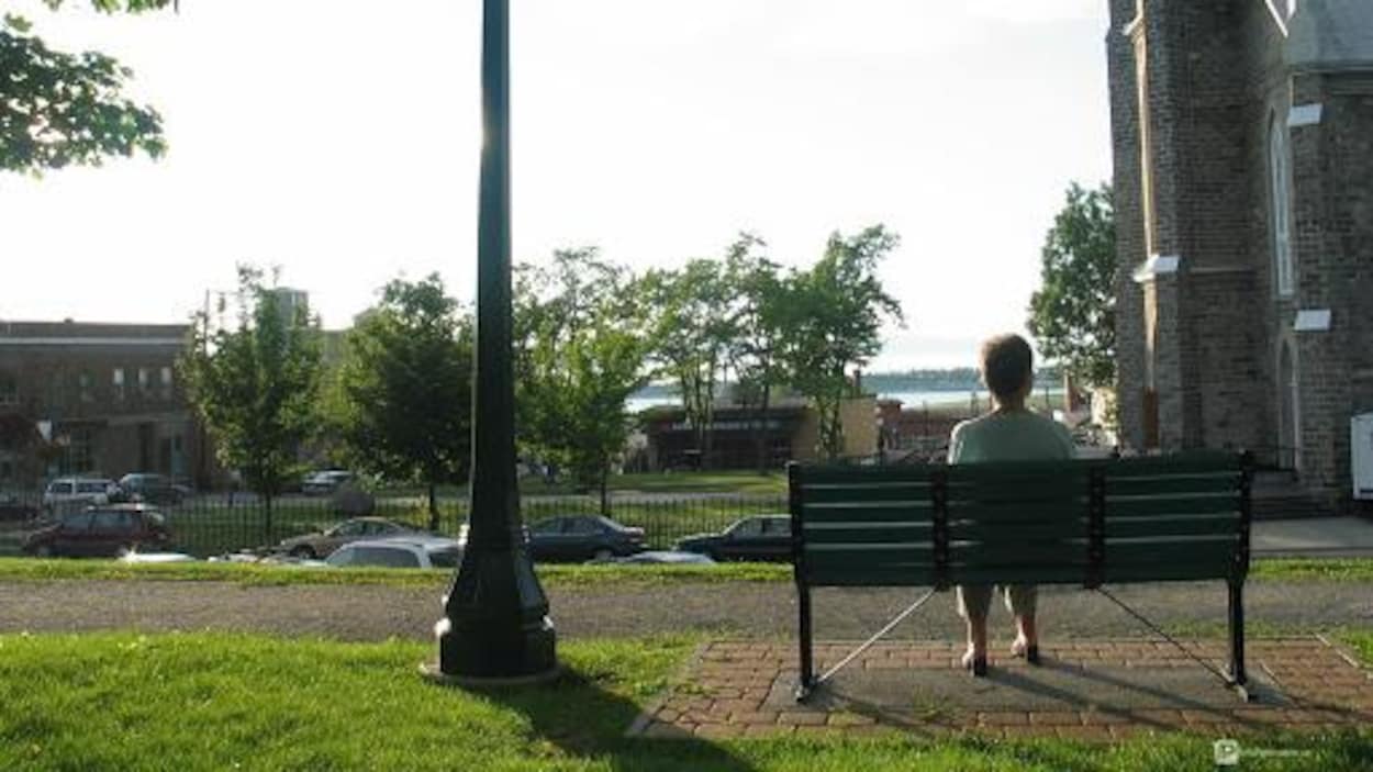 Une dame assise sur un banc de parc au Parc Blais.