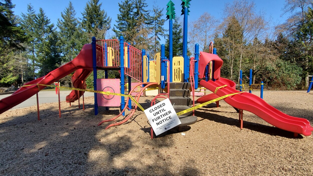 Des rubans jaunes et une affiche interdisent l'accès à une aire de jeu pour enfants.