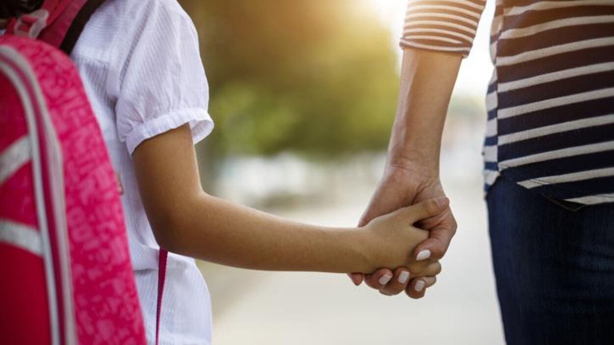 Une mère tient la main de sa fille.