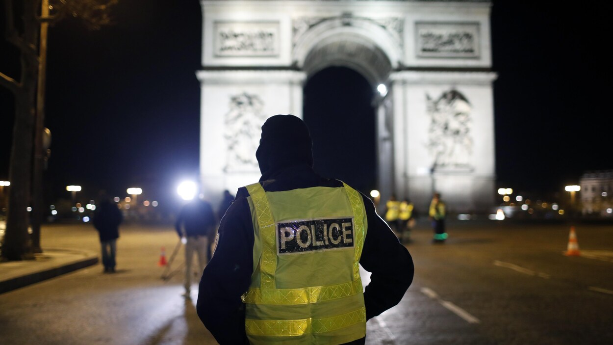 Un policier se tient sur l'avenue des Champs Elysées à côté de l'Arc de Triomphe à Paris.