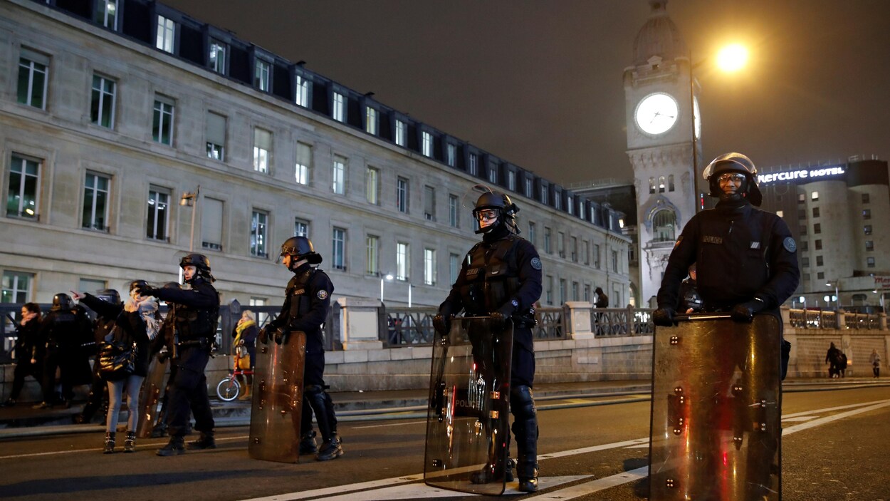 Des policiers antiémeute tiennent leurs boucliers dans la rue.