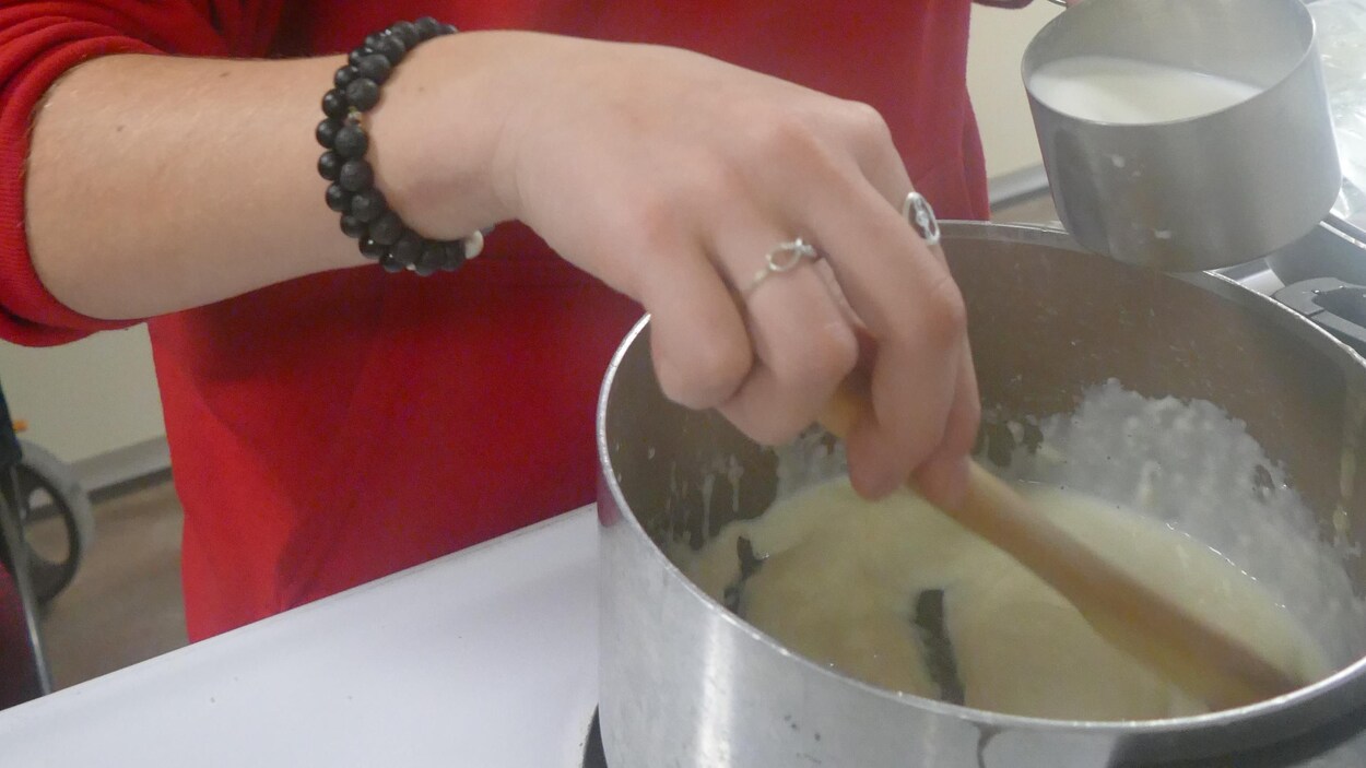Une jeune fille ajoute du lait dans une casserole.