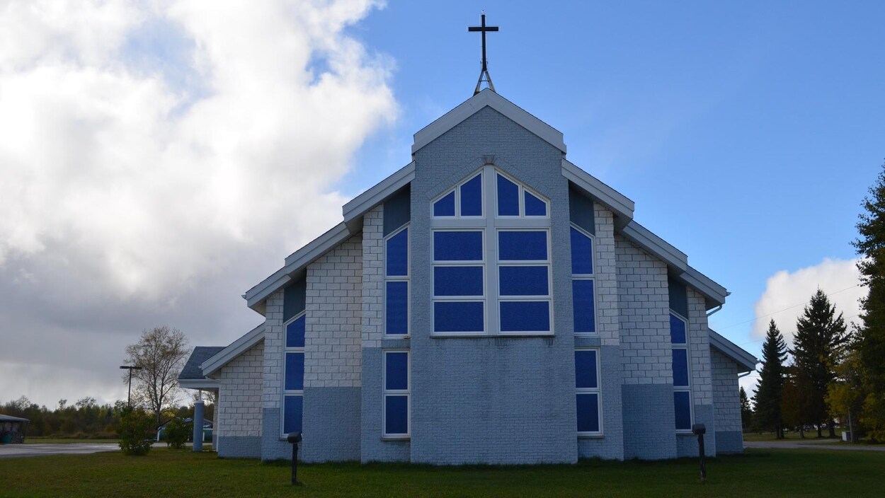 Une église au toît de laquelle se dresse une croix Une église au toît de laquelle se dresse une croix