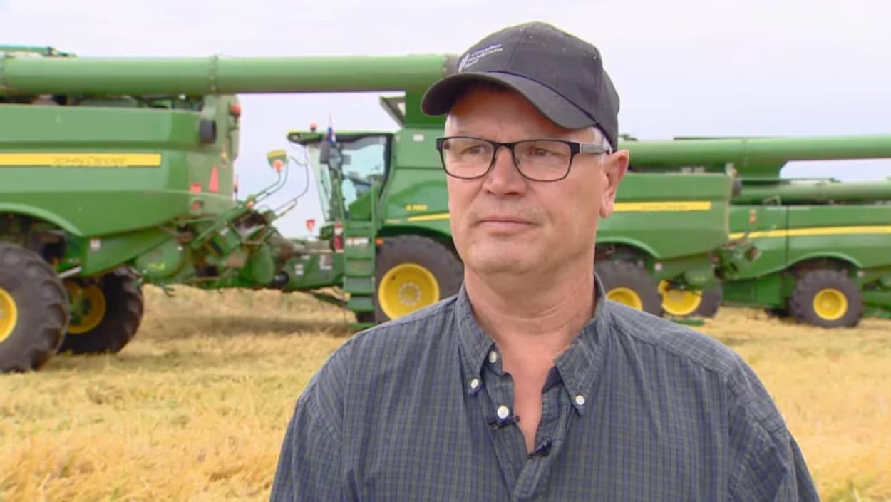 L'agriculteur Shaun Galloway dans un champ devant une moissonneuse-batteuse.