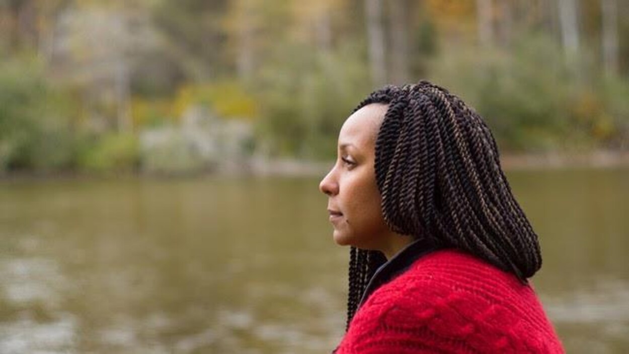 Une dame regarde le large, près d'une rivière.