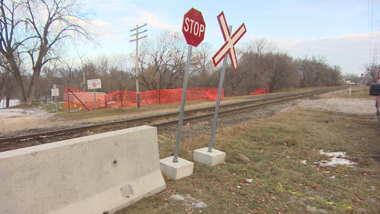 Un chemin de fer et un panneau stop, avec à côté, un bloc de béton.