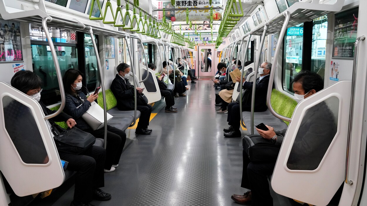 Des passagers portant des masques de protection dans un train à Tokyo.