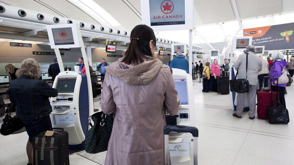 Des voyageurs s'enregistrent à un kiosque.