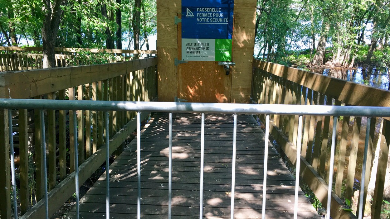 Une passerelle en bois qui est inaccessible aux passant puisqu'une affiche indique qu'elle est fermée au public.