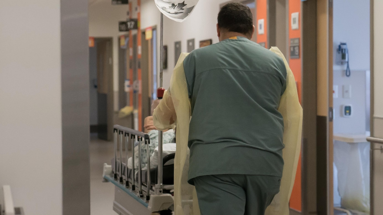 Un préposé au bénéficiaire pousse un patient sur une civière.