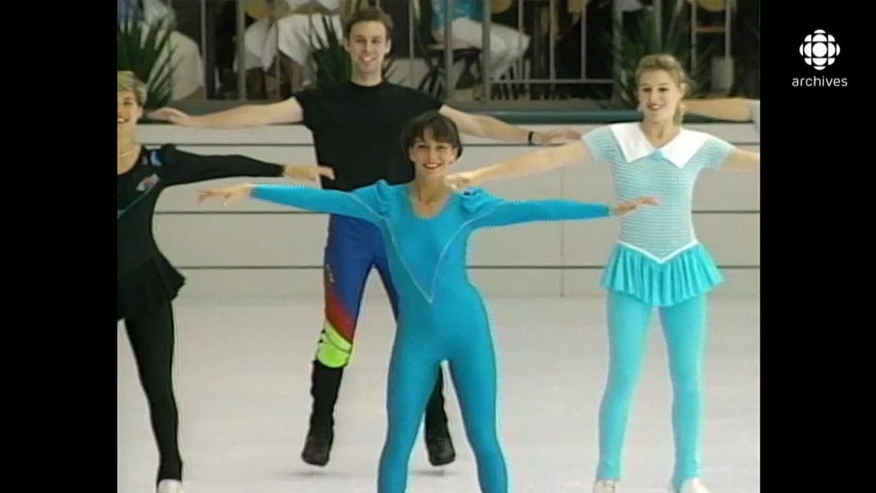 Quatre patineurs en prestation sur une patinoire intérieure, dont deux portant des léotards fluos