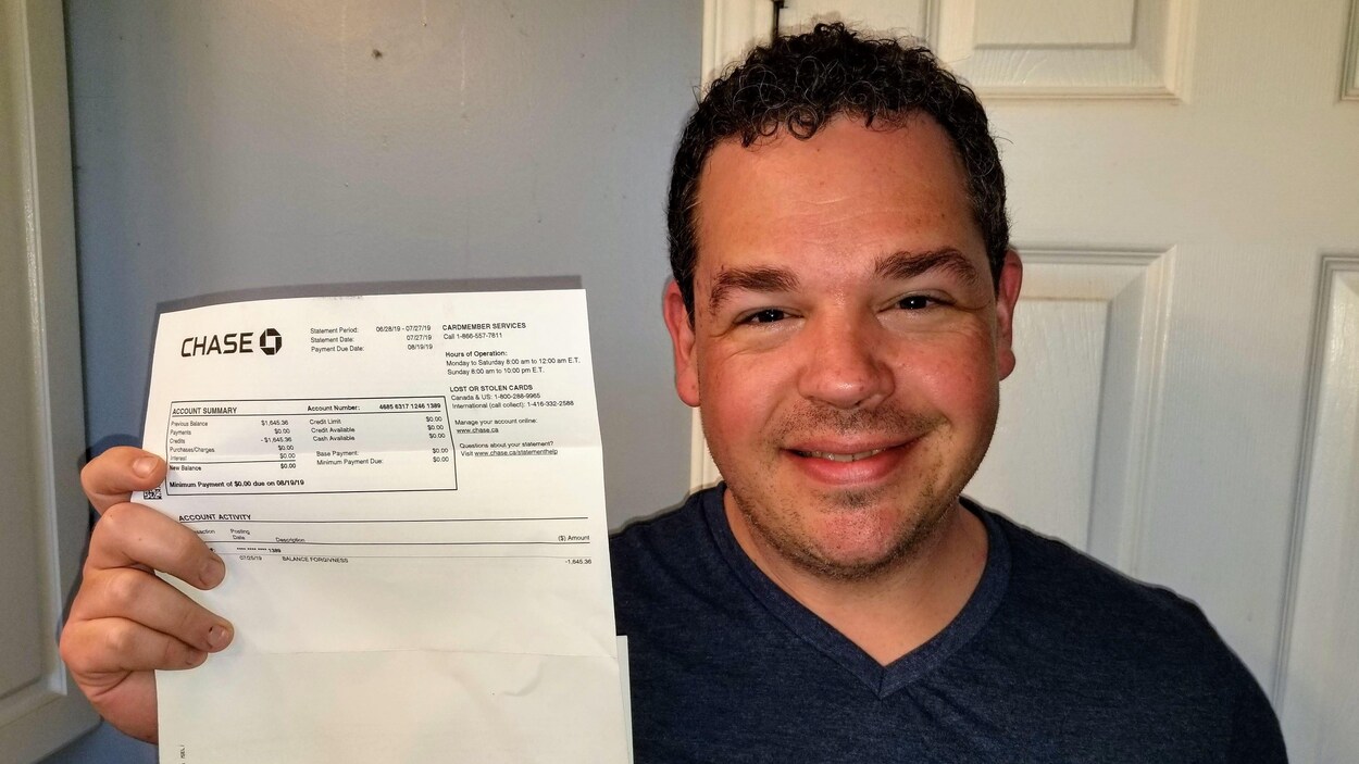 Gros plan d'un homme qui montre un relevé de carte de crédit, sourire aux lèvres.