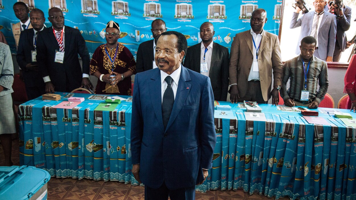 Paul Biya sourit dans un bureau de vote.