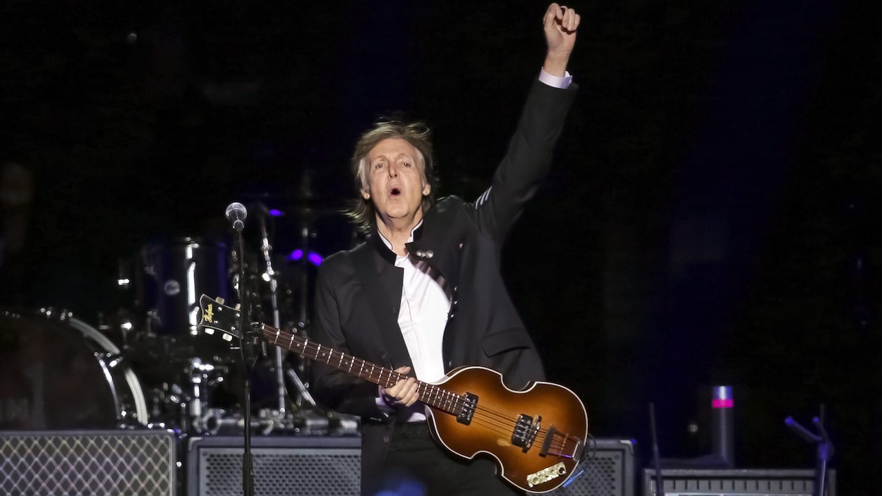 Paul McCartney tient sa guitare d'une main et lève le poing de l'autre, lors d'un concert en 2017. Paul McCartney tient sa guitare d'une main et lève le poing de l'autre, lors d'un concert en 2017.