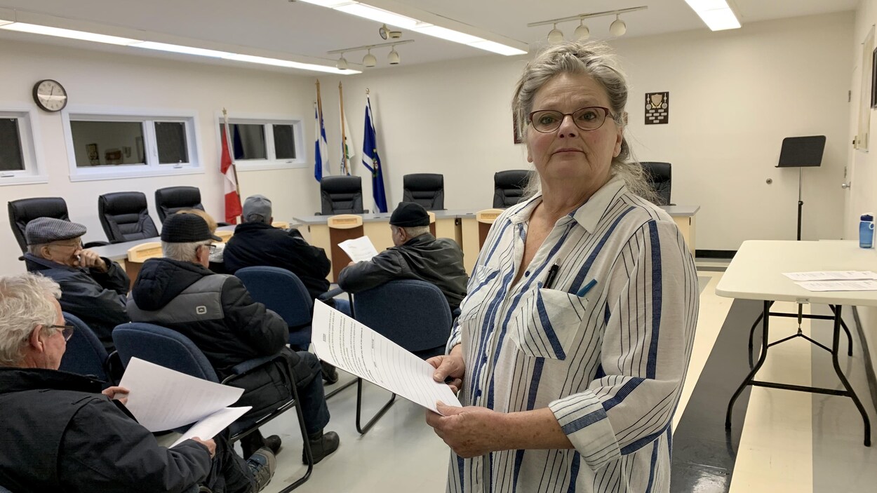 La dame debout dans la salle du conseil municipal avec la pétition dans les mains.