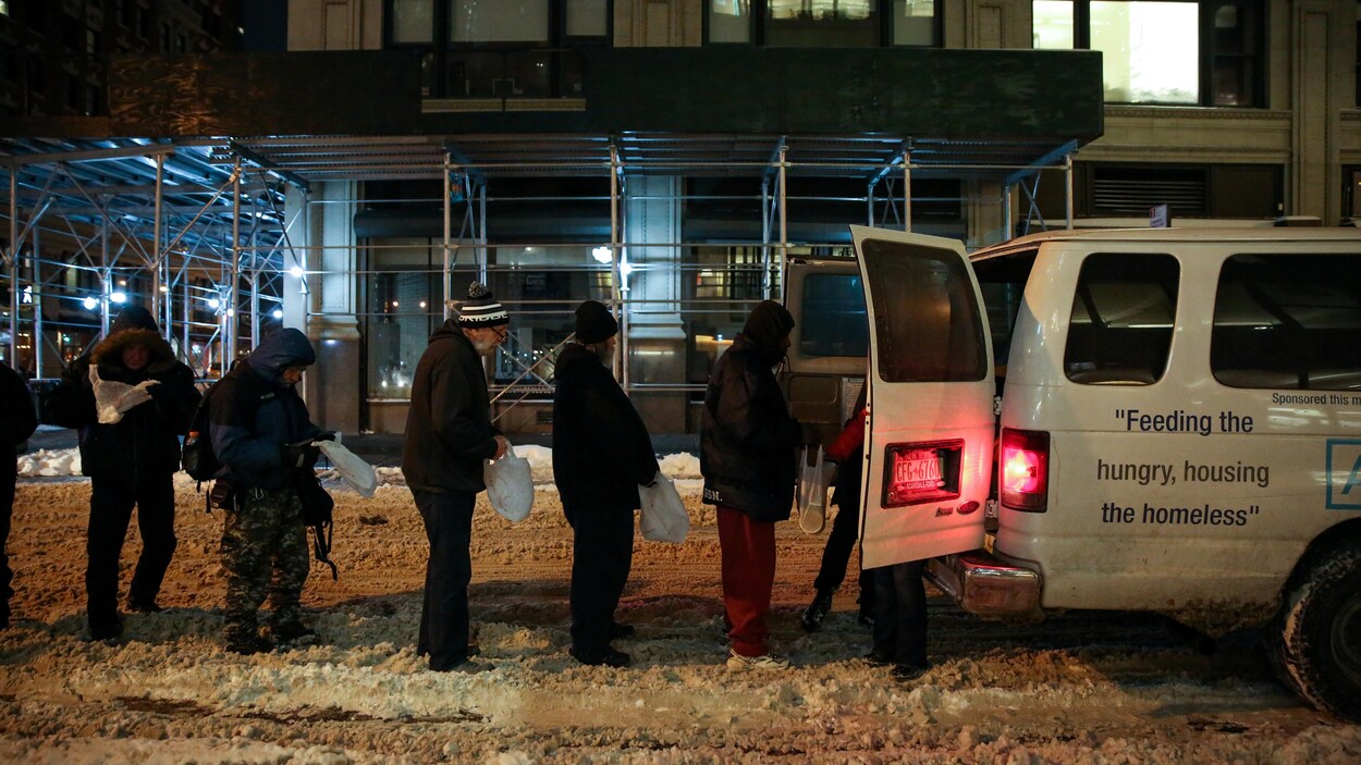 Des gens font la queue dans la rue pour recevoir de l'aide.
