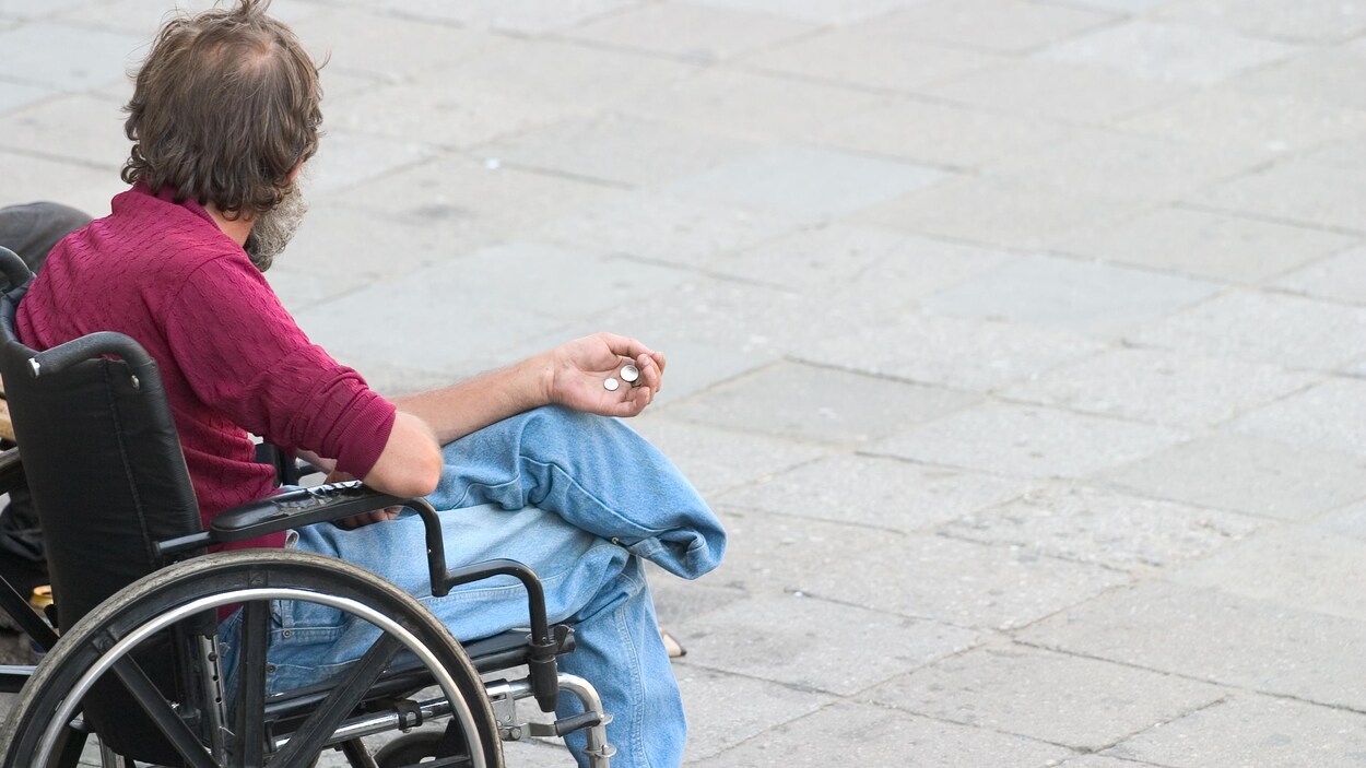 Un homme handicapé en fauteuil roulant tend la main aux passants. Un homme handicapé en fauteuil roulant tend la main aux passants.