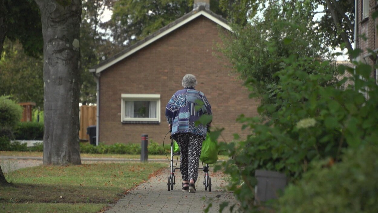 Une personne marche derrière son déambulateur.