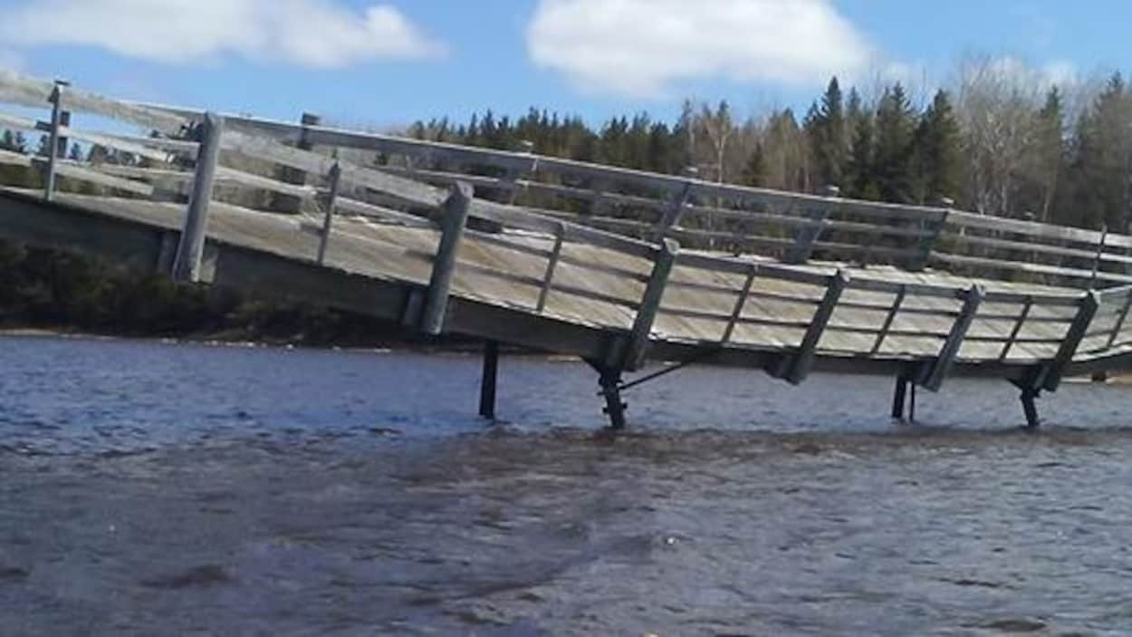 La passerelle du Pays de la Sagouine inclinée vers l'eau avec un kayak à l'avant-plan.
