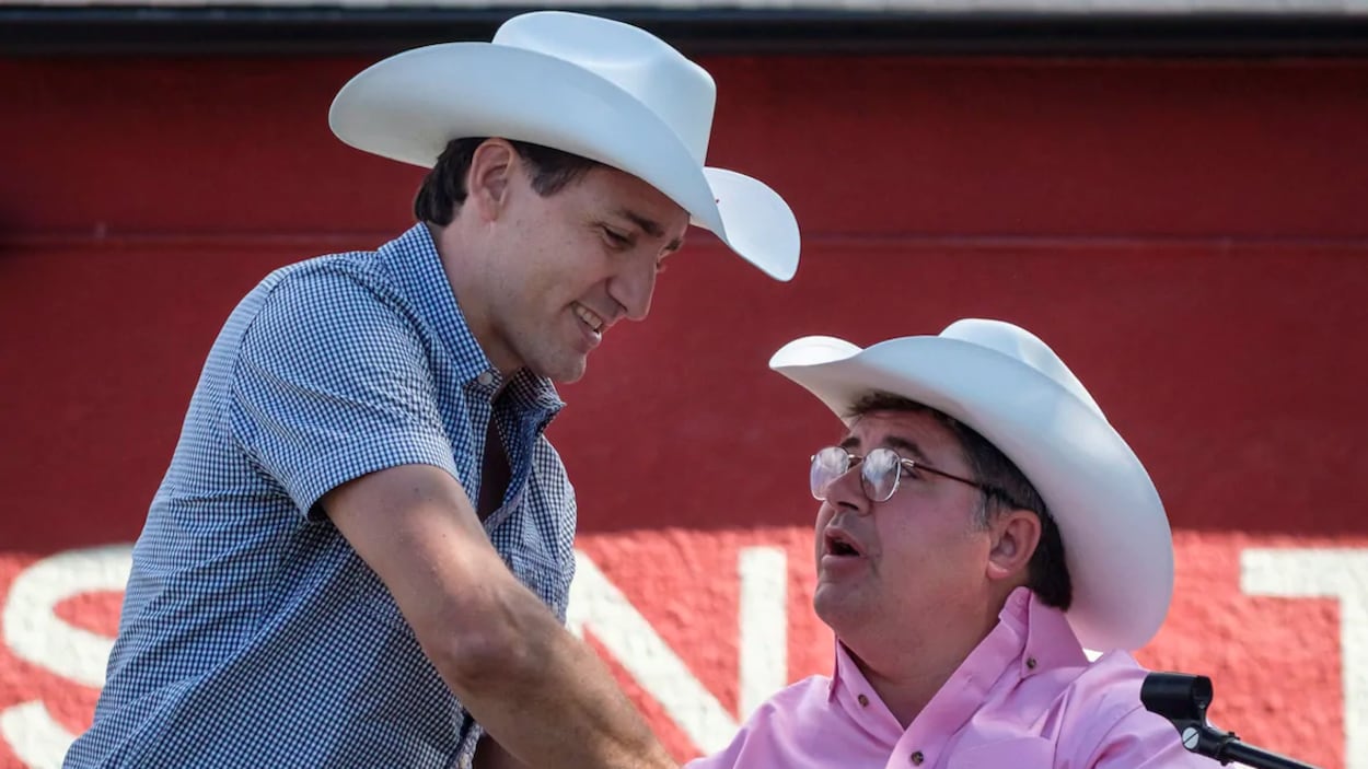Justin Trudeau serre la main de Kent Hehr, un député en fauteuil roulant. Les deux portent un chapeau de cowboy.