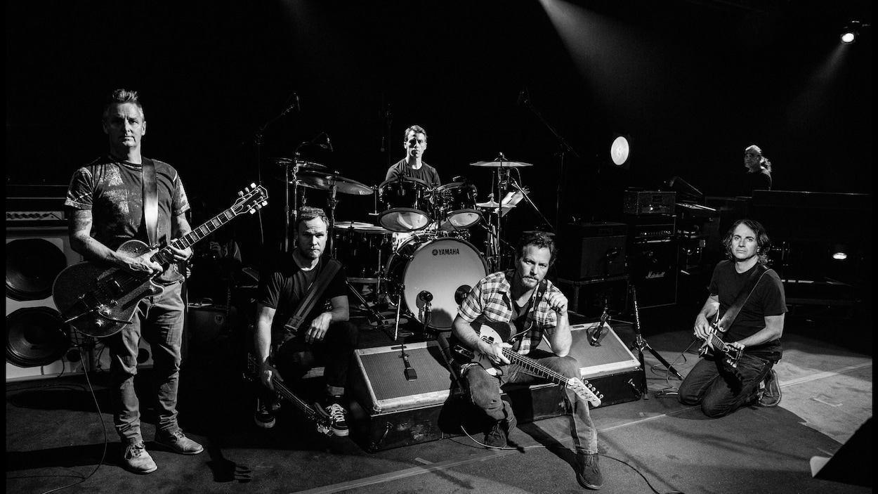 Photo en noir et blanc sur laquelle cinq musiciens sont photographiés avec leurs instruments.