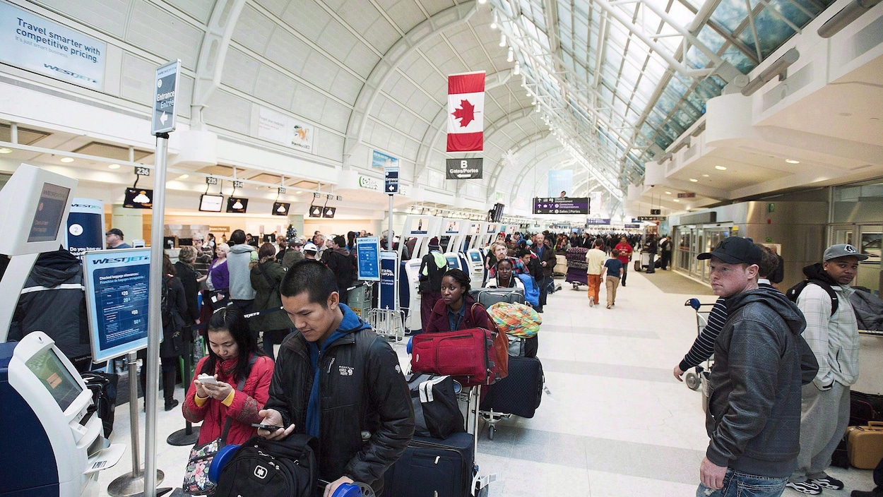 Des gens font la file à l'aéroport Pearson de Toronto Des gens font la file à l'aéroport Pearson de Toronto