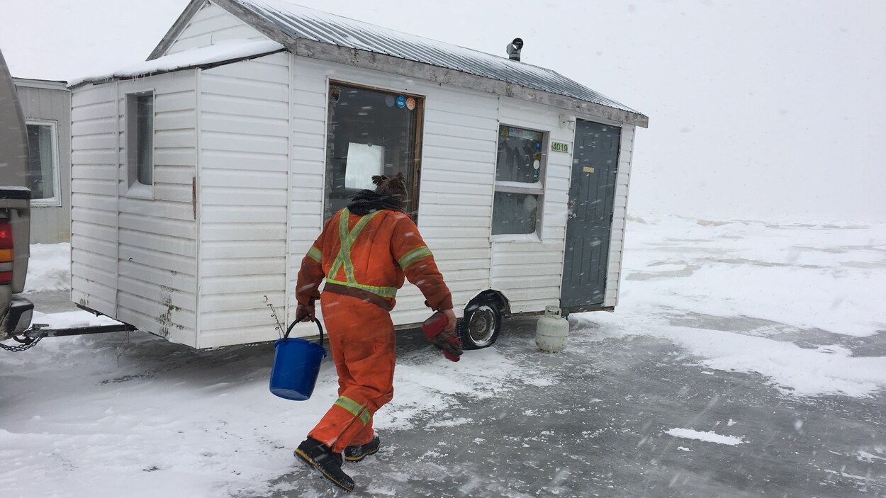 Un homme embarque son matériel de pêche dans sa cabane. Un homme embarque son matériel de pêche dans sa cabane.