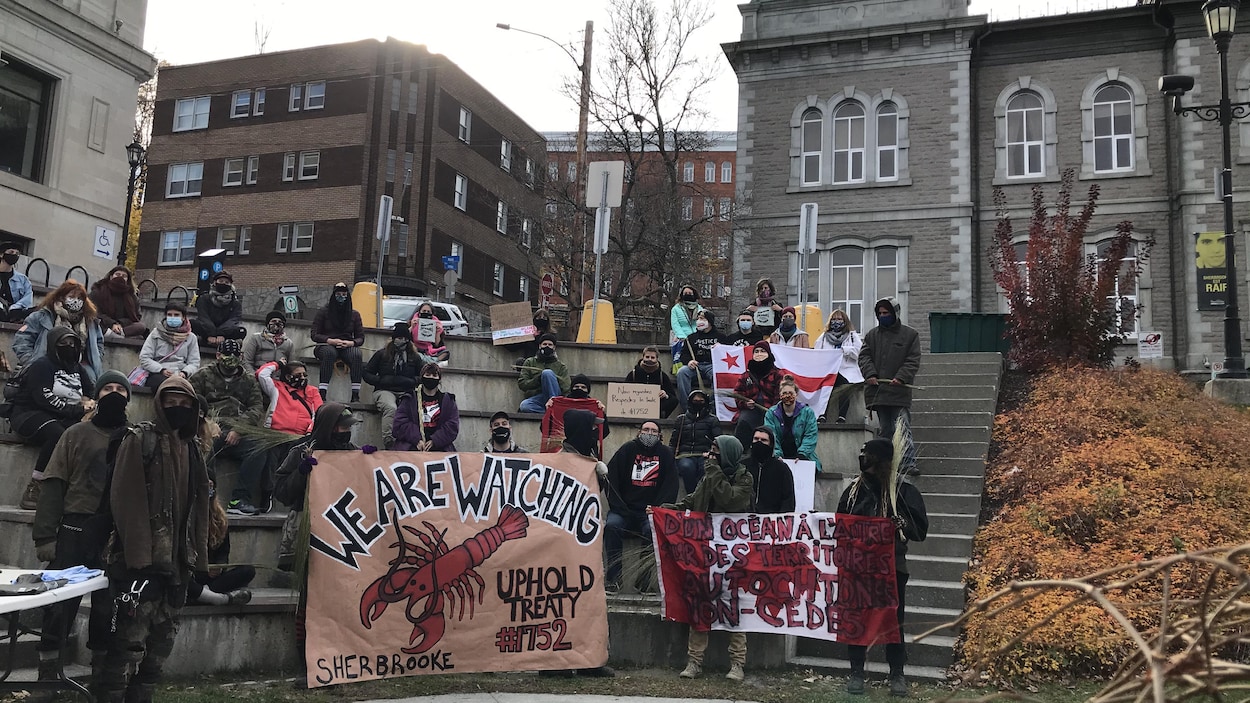 Des manifestants sont rassemblés avec une banderole montrant un homard.