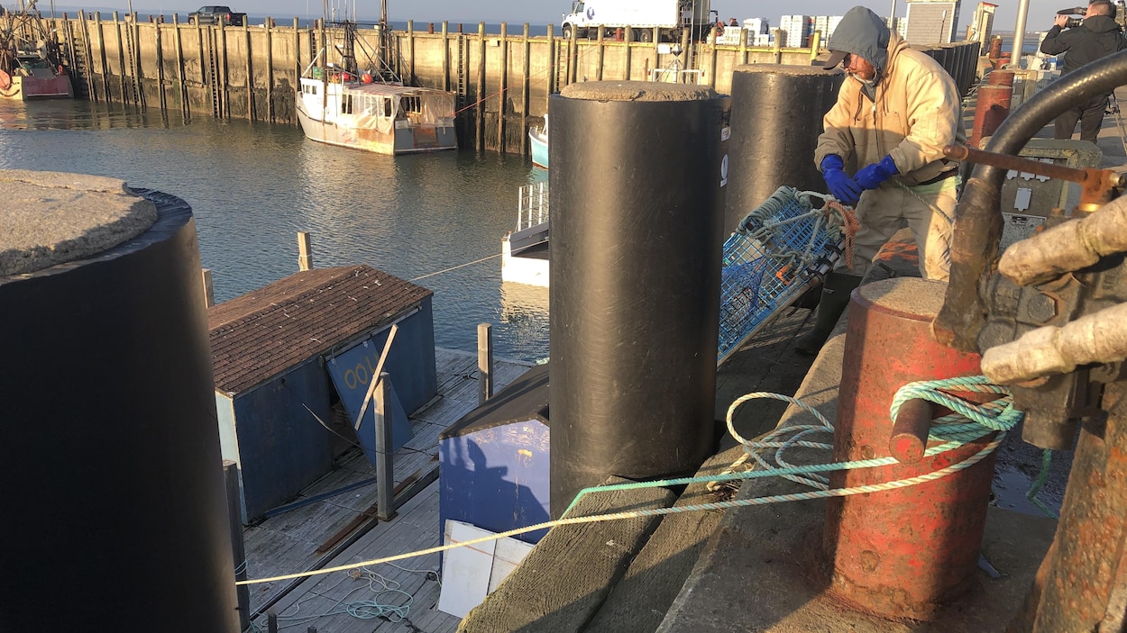Un pêcheur remplit son bateau de casiers de homard.