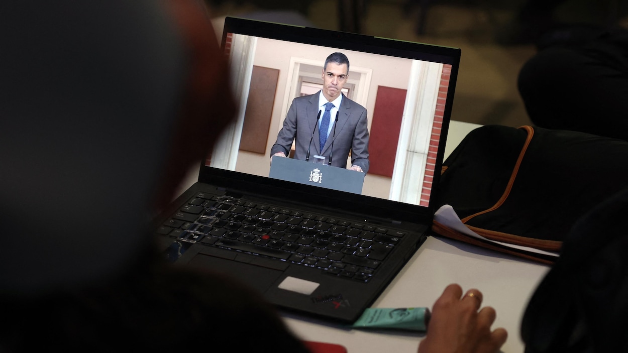 Un journaliste regarde dans son ordinateur une déclaration télévisée de Pedro Sanchez.