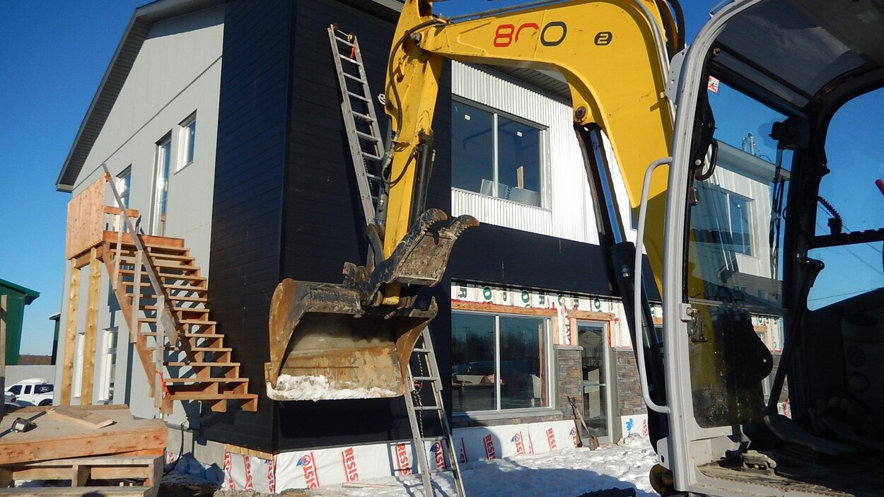Une pelle mécanique devant un bâtiment en construction. Une pelle mécanique devant un bâtiment en construction.