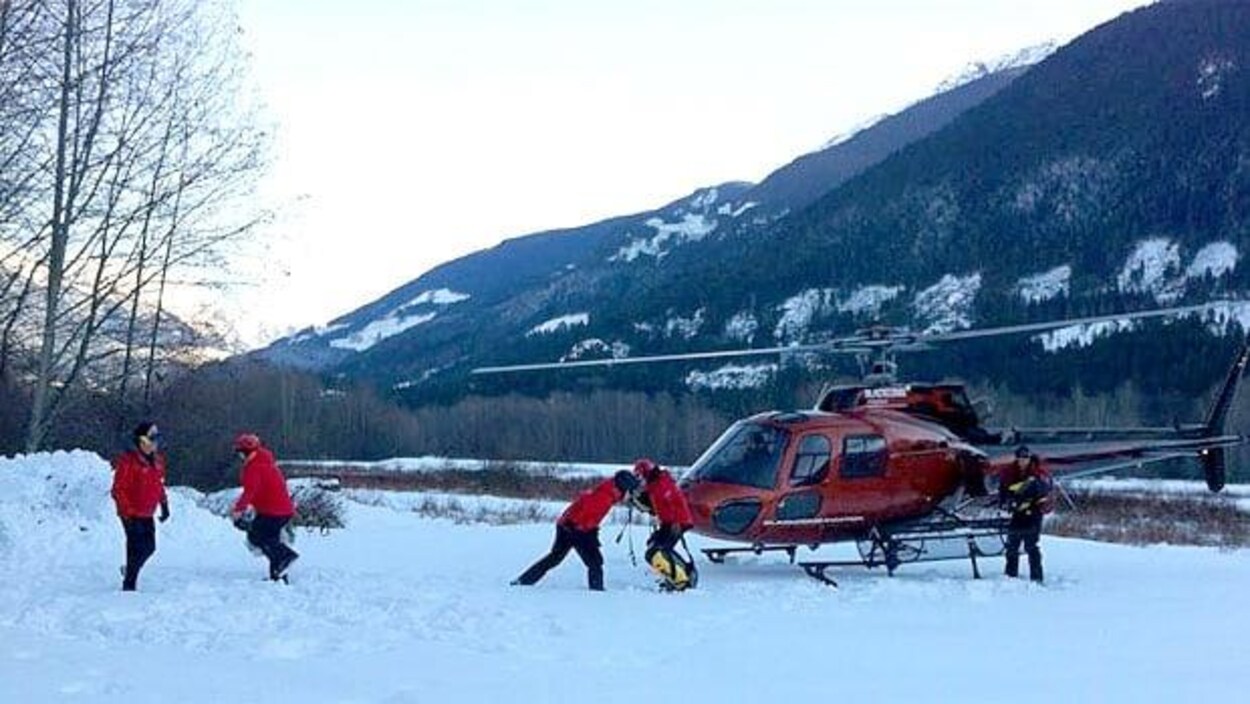 Une équipe de recherche et sauvetage entoure un hélicoptère posé sur une montagne enneigée en Colombie-Britannique.