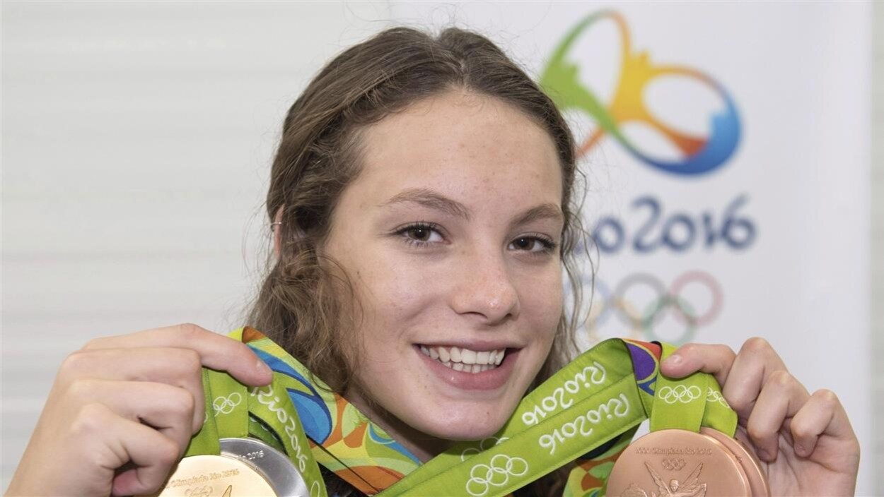 Penny Oleksiak pose avec quatre médailles, avec un grand sourire