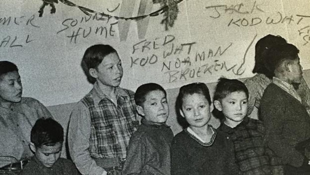 Des enfants du pensionnat autochtone Baptist Mission School sont debout devant un mur un jour de Noël à Whitehorse.
