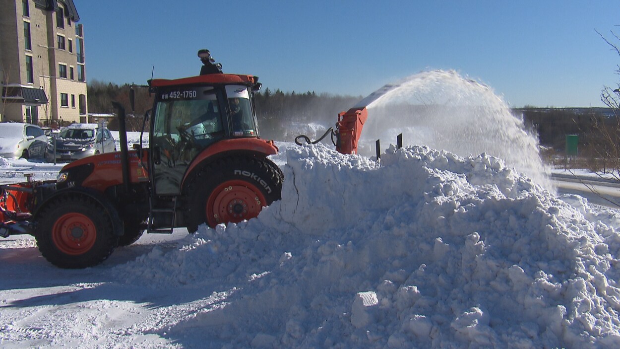 Un camion de déneigement souffle la neige.