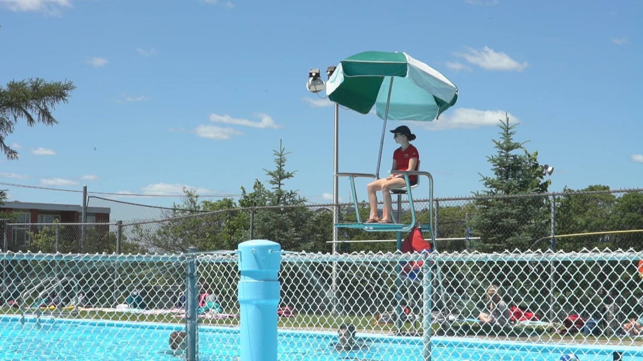 Une jeune femme surveille une piscine publique.