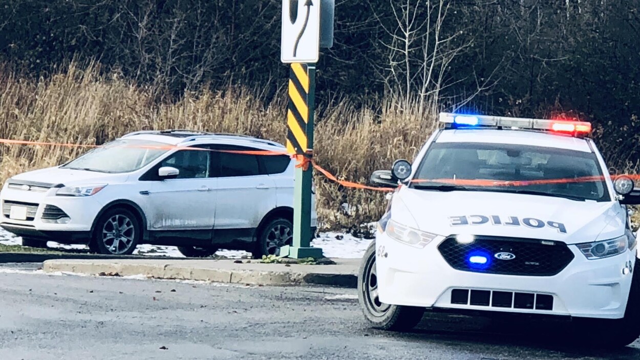 Une voiture de police est stationnée près d'un autre véhicule.