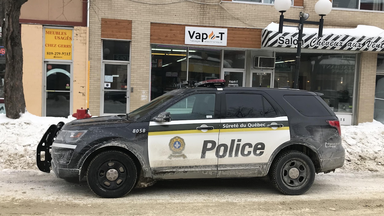 Une voiture de la Sûreté du Québec est stationnée devant des commerces.