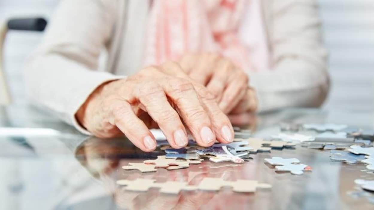 Gros plan sur la main d'une personne âgée qui joue à un casse-tête.