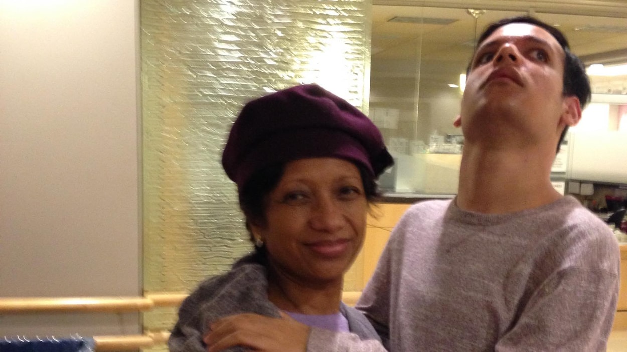 Une femme avec un béret sur la tête debout enlacé avec son fils de 31 ans.