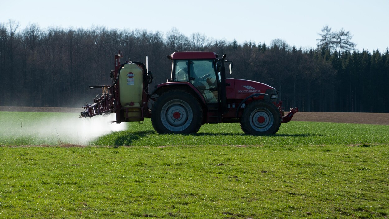 Un agriculteur arrose un champ de pesticides.