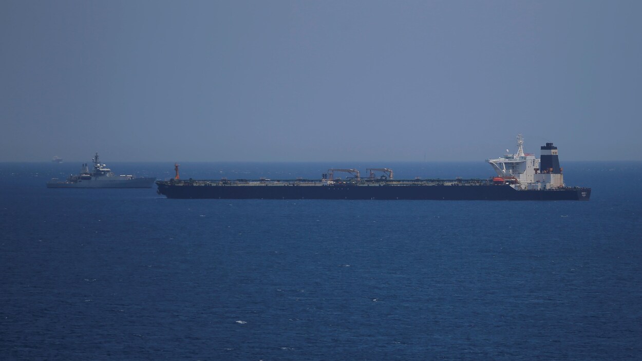 Un navire militaire britannique est visible derrière un pétrolier iranien en pleine mer.