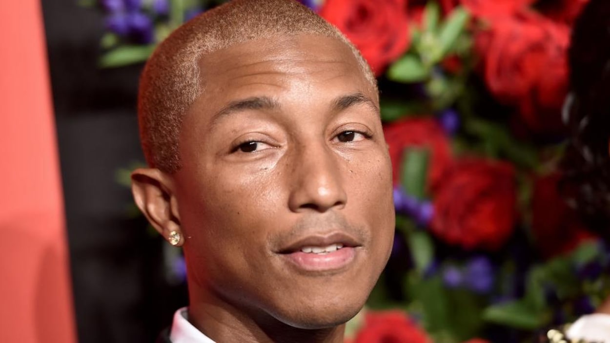 Gros plan sur Pharrell Williams avec des roses rouges en fond.