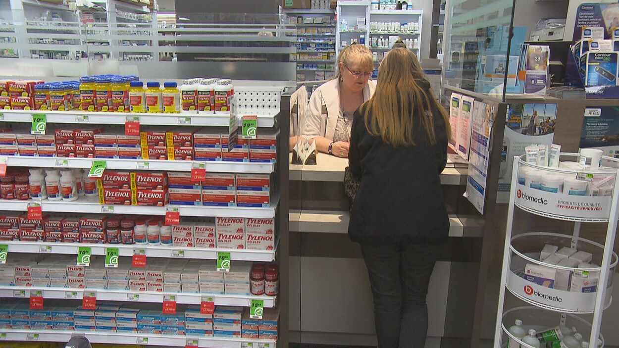 Une pharmacienne s'adresse à une cliente au comptoir.