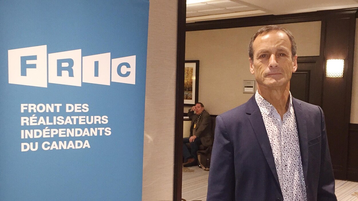 Phil Comeau à côté d'une affiche du FRIC.