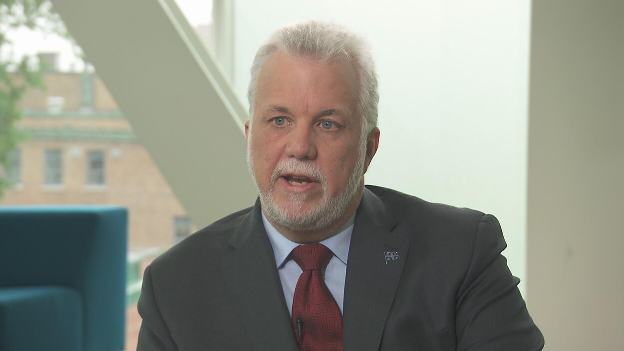 Philippe Couillard répond aux questions d'un journaliste à la caméra. Philippe Couillard répond aux questions d'un journaliste à la caméra.