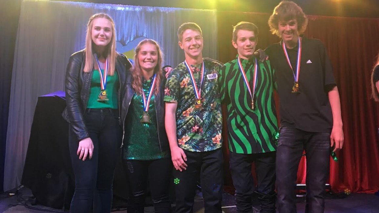 Cinq gagnants et leur médaille sur la scène.