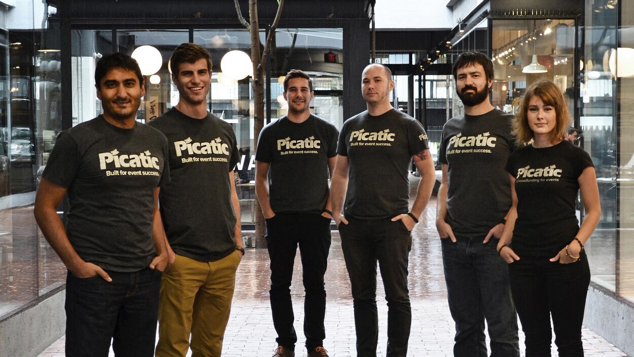 Cinq hommes et une femme disposés en arc de cercle dans le hall d'un bâtiment. Tous portent des T-shirts avec l'inscription «built for event success». Cinq hommes et une femme disposés en arc de cercle dans le hall d'un bâtiment. Tous portent des T-shirts avec l'inscription «built for event success».