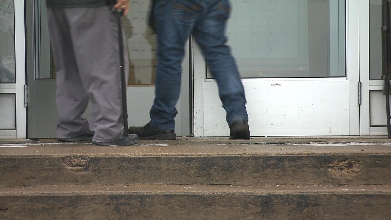 Les jambes de deux hommes devant une porte.