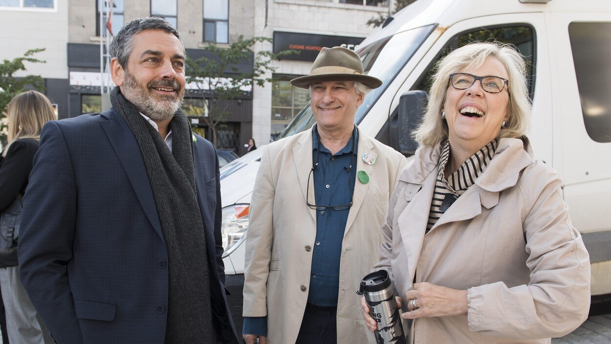 Pierre Nantel, Daniel Green et Elizabeth May devant un véhicule stationné dans une rue du centre-ville de Montréal.